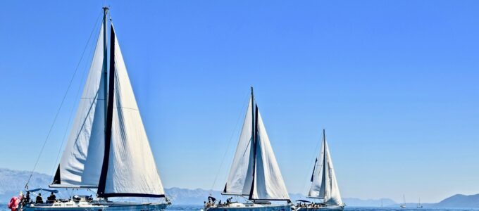 three sail boats on water during daytime